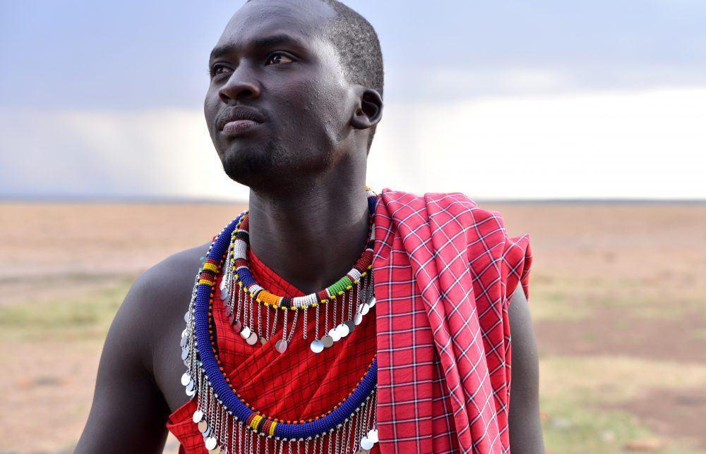 Maasai man in traditional clothes looking into the distance in Masai Mara, Kenya.