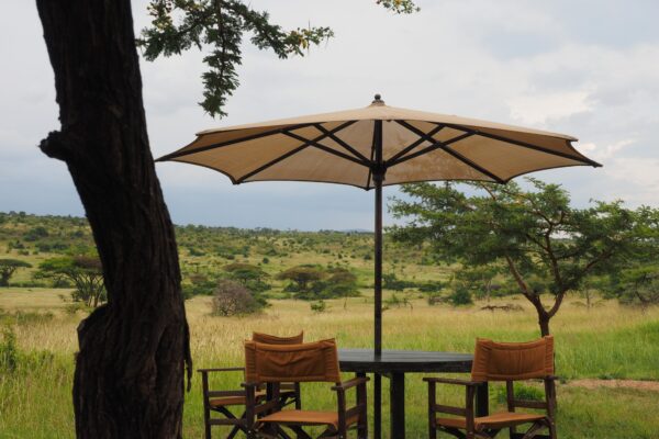 Dining table with parasoll on the savannah at Basecamp Explorer Wilderness Camp in Kenya.